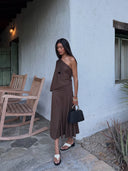 @princessmyint wearing the Belle Anna Arden Dress in Brown, an asymmetrical one-shoulder midi dress featuring a draped overlay bodice, open back, fitted waist, and softly flared skirt.