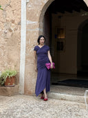 Customer wearing the Hela Dress, a purple maxi styled for a wedding guest look in Europe.